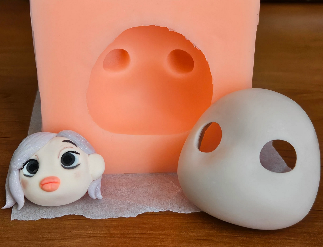 The basic face mask next to the silicone mould made using it. On the far left, the little head made in January out of modelling clay, as a souvenir.